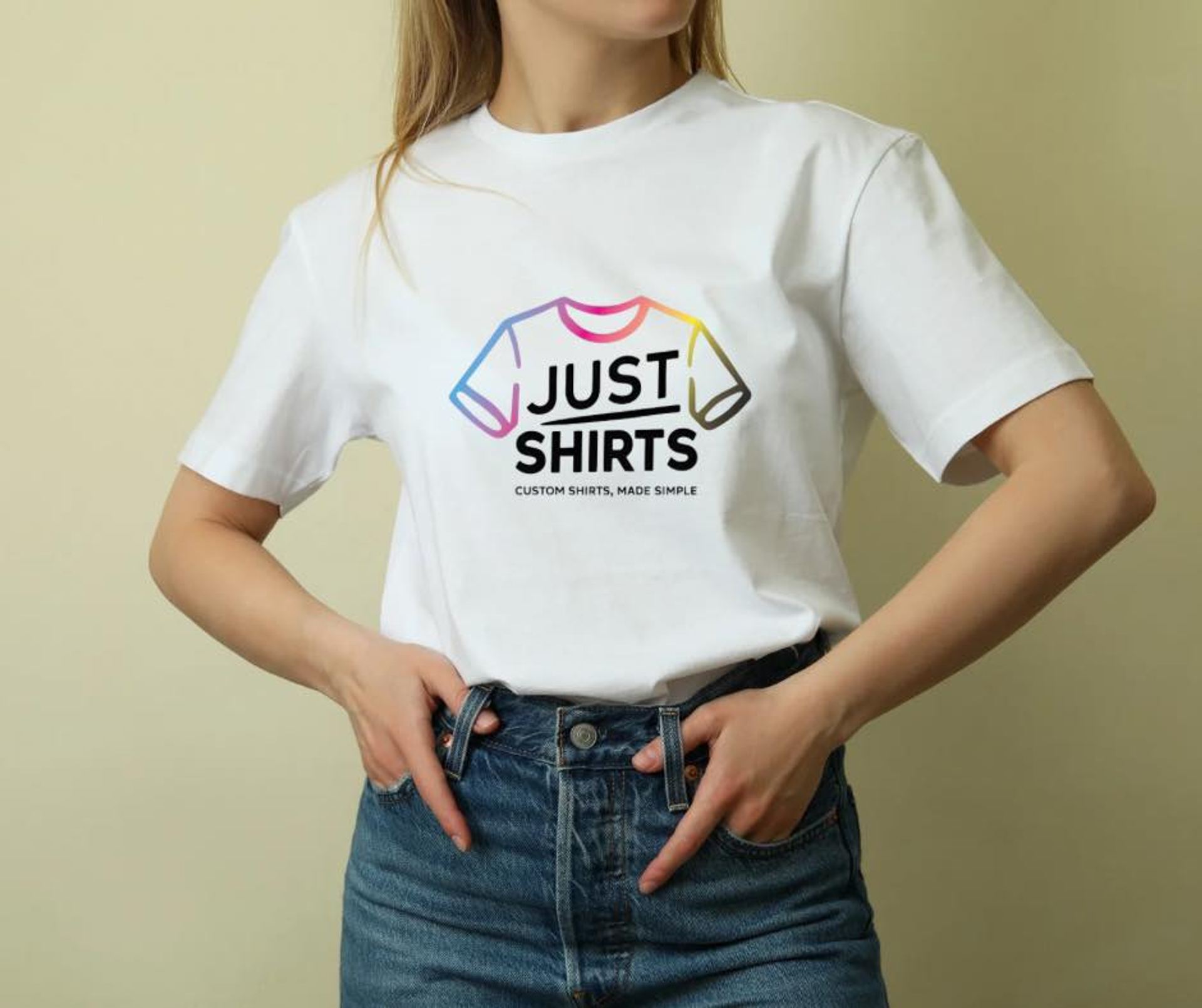 A person wearing a white tee with the colorful Just Shirts logo printed across the chest