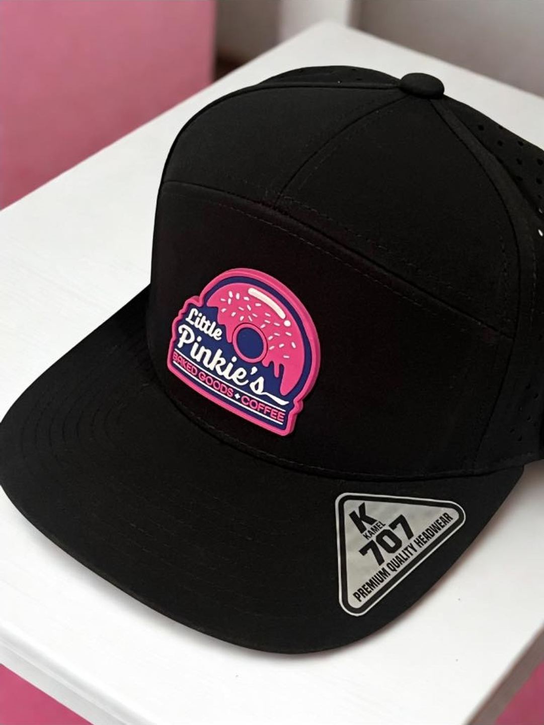 Black flat-brim hat with a pink rubber Little Pinkie's donut patch on the front