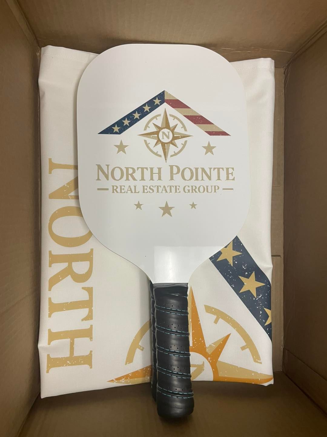 White pickleball paddle and sleeve printed with the North Pointe Real Estate Group logo